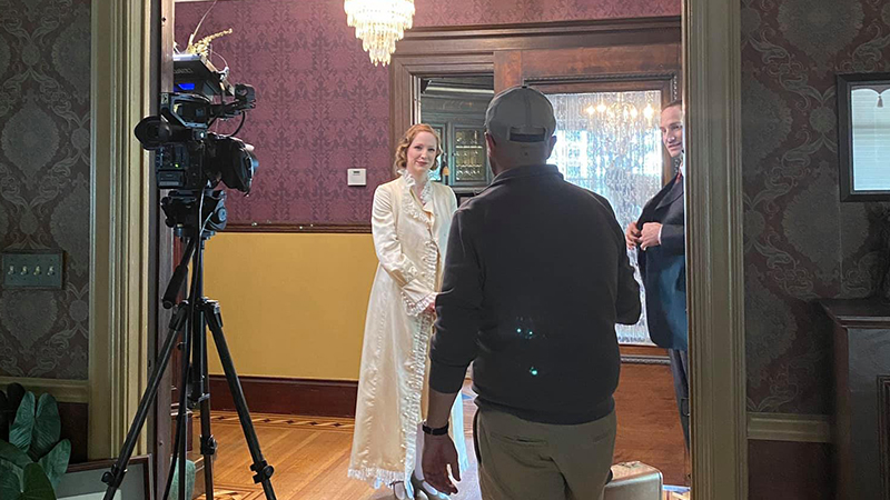 Actors pose in front of a camera rolling.
