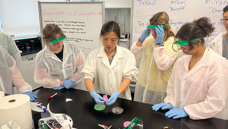 Dr. Huan Gu (center) leads a lesson in the laboratory.