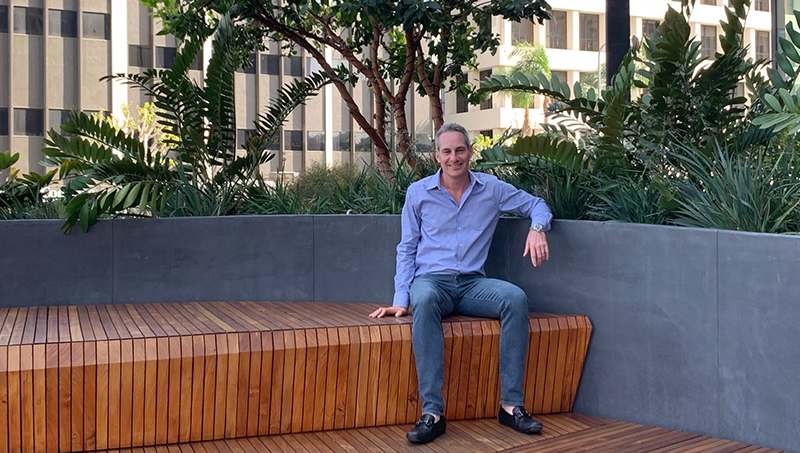 Alan Roberts posing for a photo, sitting on a bench.
