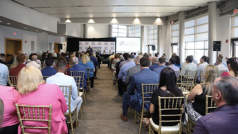 Photo from the back of the awards ceremony showing attendees sitting on either side of an aisle.