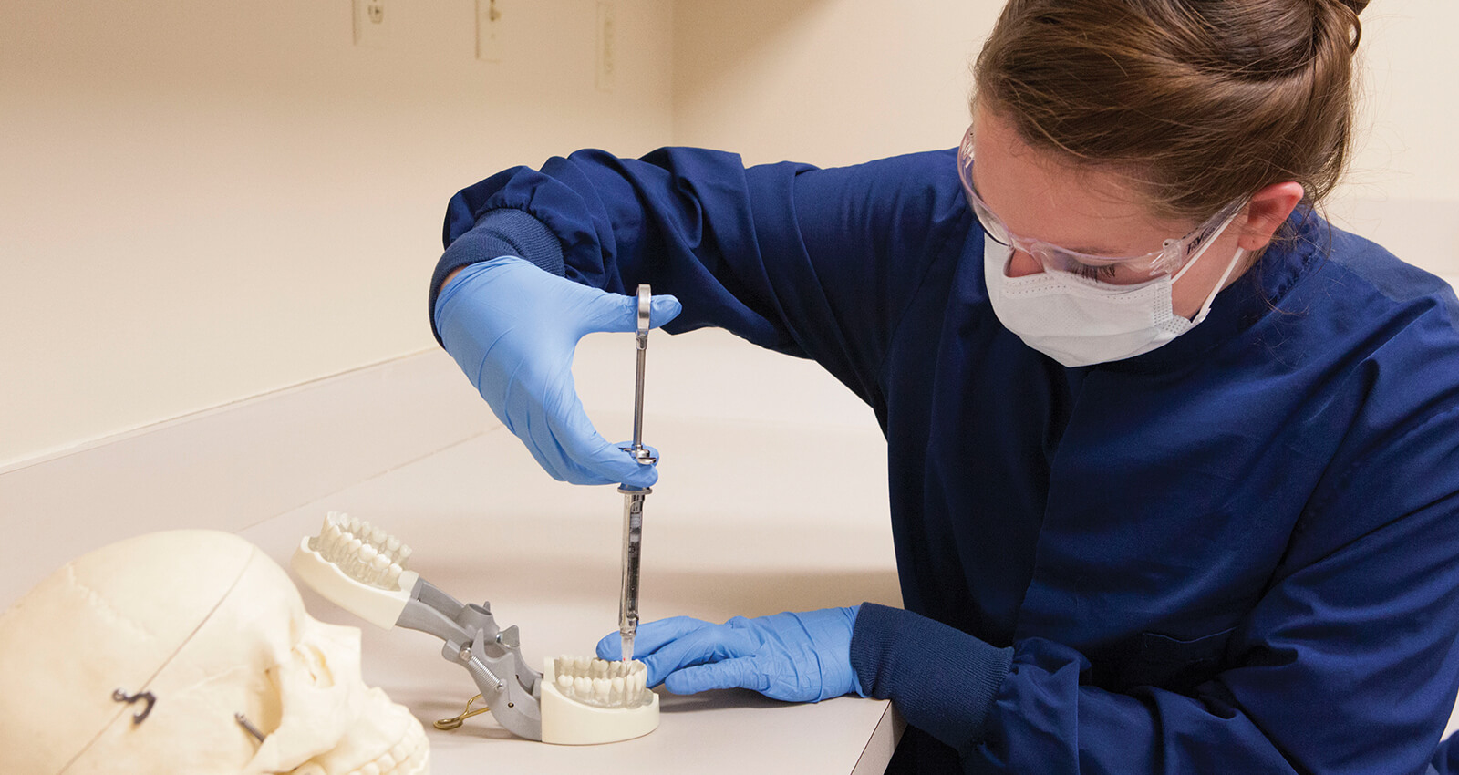 A dental hygiene student injects Novocain into a test jaw in the lab.