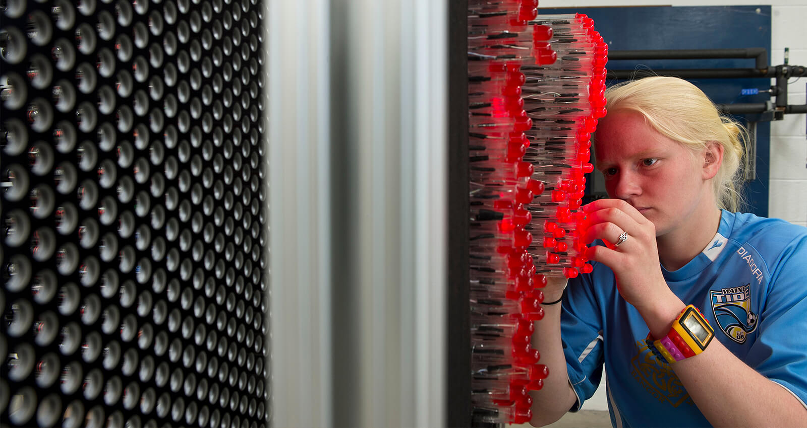 A student working on an electronic component prototype containing red LEDs, wiring, and discrete electronic components.