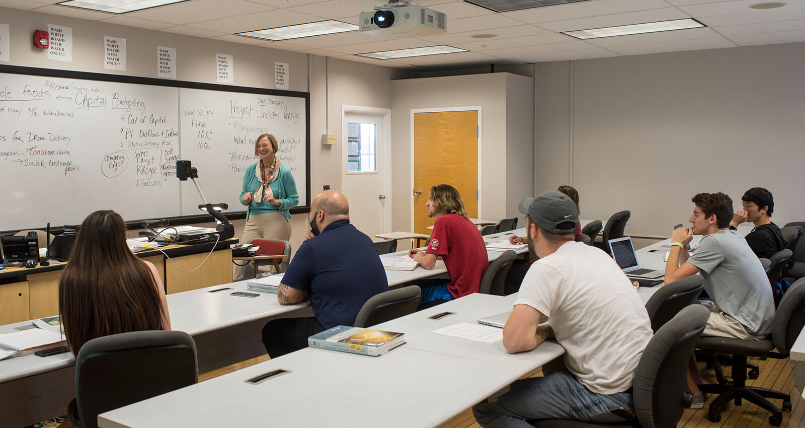 Female professor at the front of class in front of a whiteboard