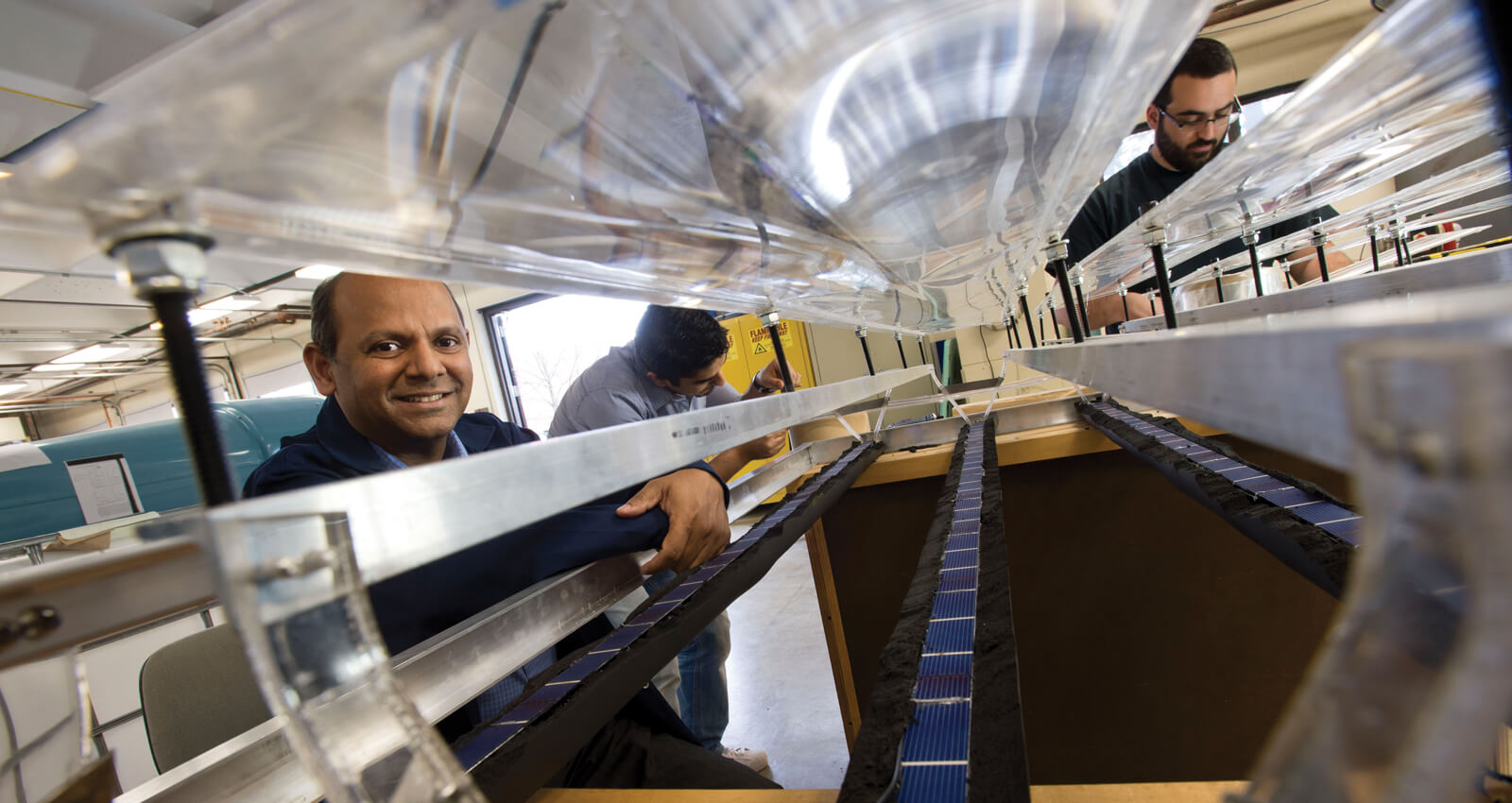 A professor and student working together on a large mechanical testing apparatus or wind tunnel setup in an industrial engineering laboratory.