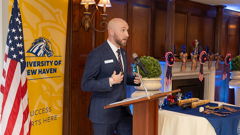 Ryan Noonan /U+0026#x27;20, /U+0026#x27;23 M.S. addresses attendees during the ceremony.