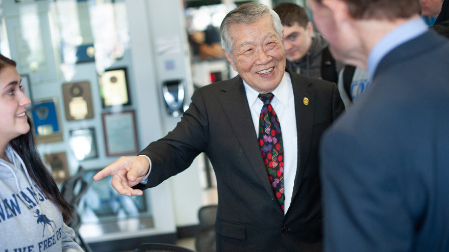 Dr. Henry Lee gestures while speaking with a lawmaker and student.