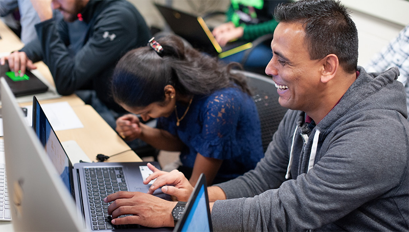 Students sitting at table with laptop.