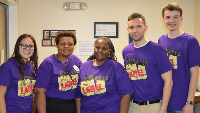 Linda Copney-Okeke, shoulder-to-shoulder, posing for a photo in matching purple /U+0026#x27;disable the label/U+0026#x27; shirts.