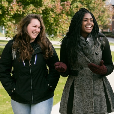 Two female students laughing while walking