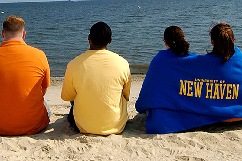 Students on beach with UNH towel